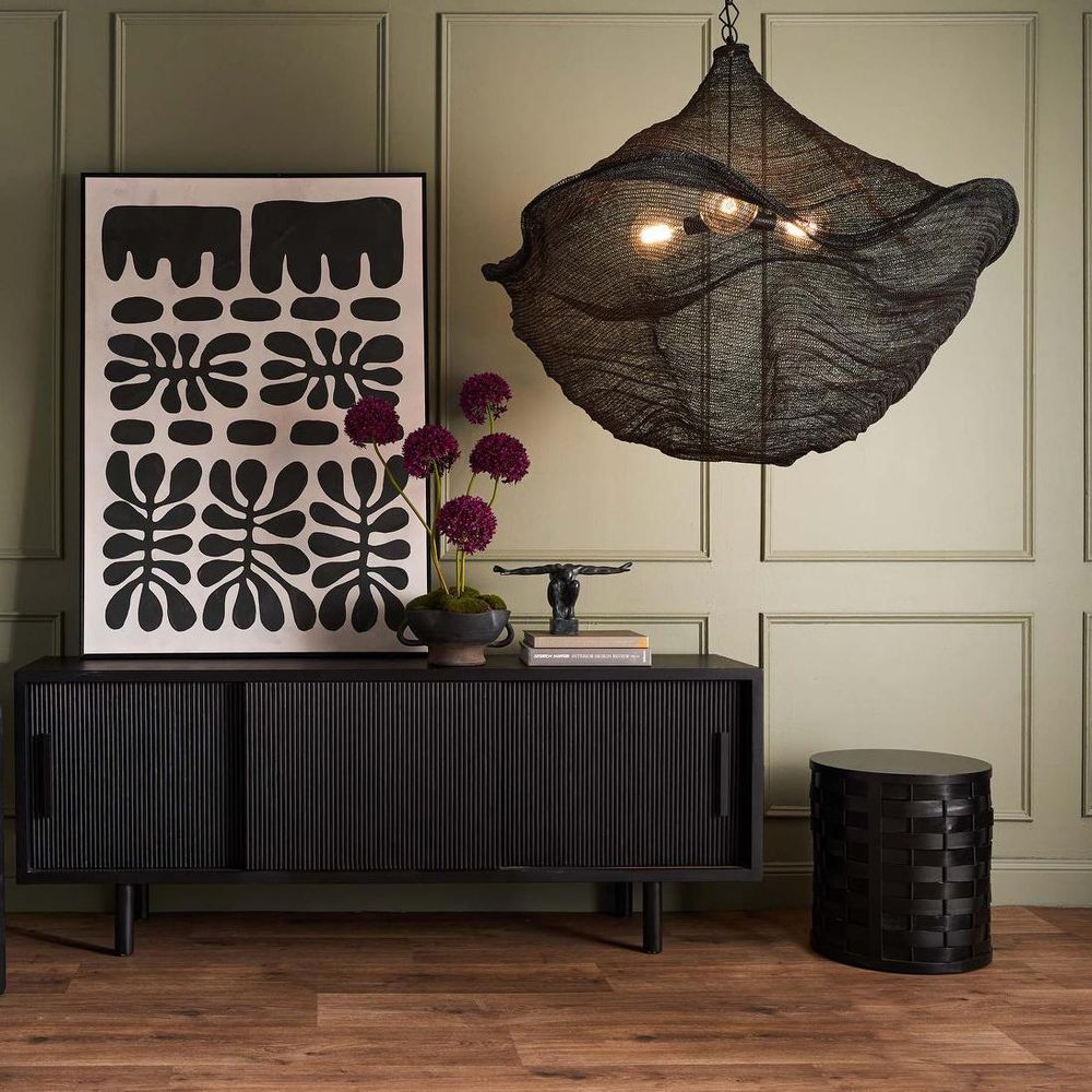 Modern interior with a black sideboard, decorative lamp, and wall art.